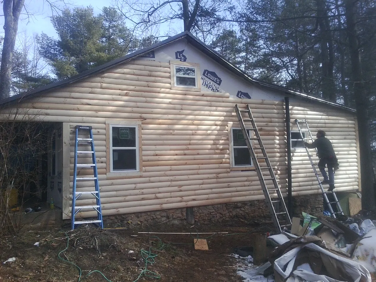 Ladders set against fresh log siding during an exterior remodel in Mason